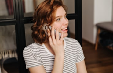 Foto/Grafik Quelle: freepik.com - Nahaufnahmeporträt des roten lockigen mädchens im gestreiften t-shirt, das am telefon spricht. © lookstudio